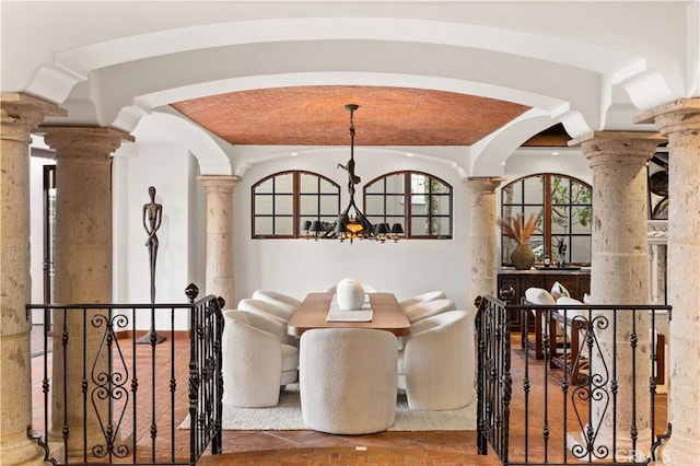 dining space featuring brick ceiling, a notable chandelier, and decorative columns