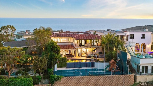 exterior space with a water view, tennis court, and a playground