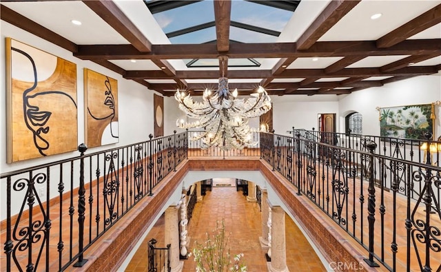 hall featuring beam ceiling, a notable chandelier, and coffered ceiling