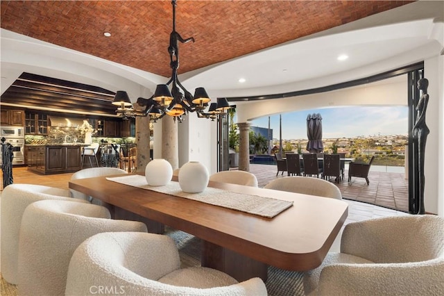 dining room featuring brick ceiling, ornate columns, a notable chandelier, and vaulted ceiling