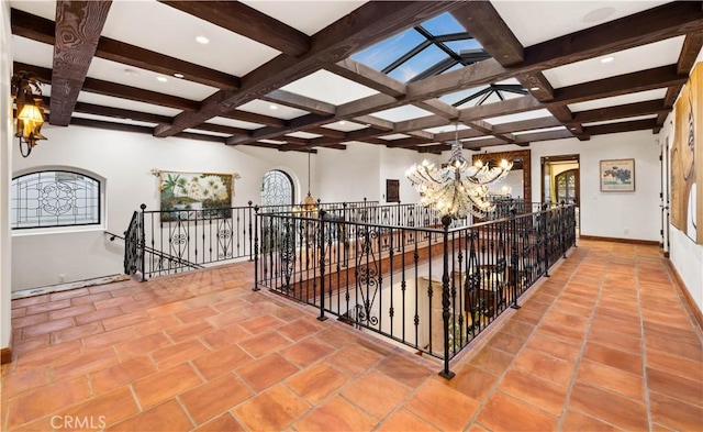 hallway with coffered ceiling, tile patterned floors, beam ceiling, and an inviting chandelier