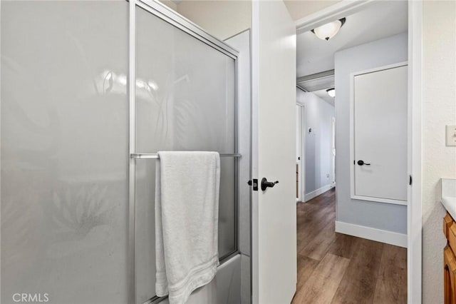 bathroom featuring hardwood / wood-style flooring, vanity, and enclosed tub / shower combo