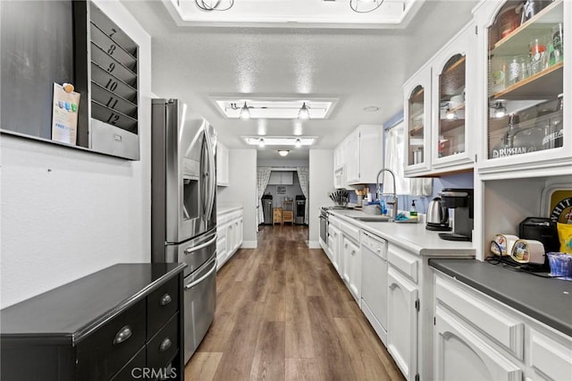 kitchen with white cabinetry, white appliances, wood-type flooring, and sink