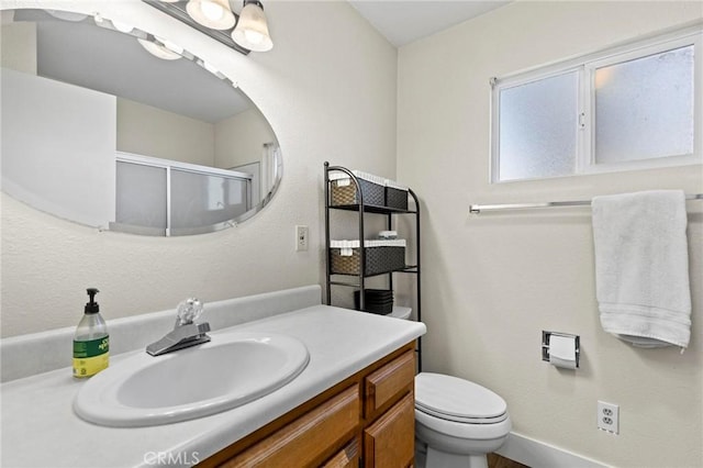bathroom with vanity, a shower with shower door, and toilet