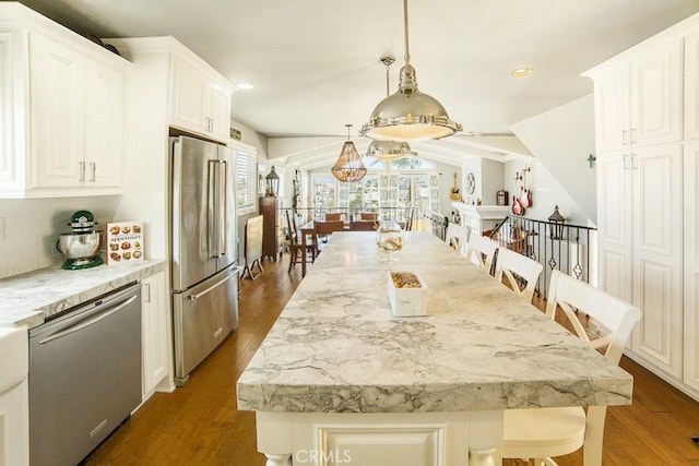 kitchen with appliances with stainless steel finishes, a breakfast bar area, white cabinetry, and pendant lighting