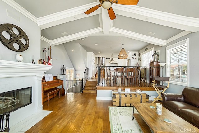 living area featuring crown molding, stairway, a ceiling fan, a brick fireplace, and wood finished floors