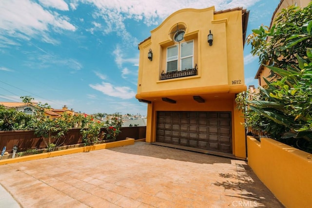 exterior space with a garage, driveway, fence, and stucco siding