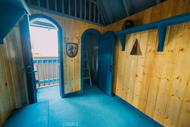 1612 Speyer Ln, Redondo Beach, CA 90278 - spare room featuring vaulted ceiling, wood walls, carpet, and arched walkways