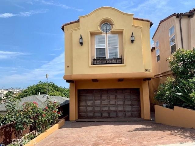 mediterranean / spanish-style home with a garage, decorative driveway, and stucco siding