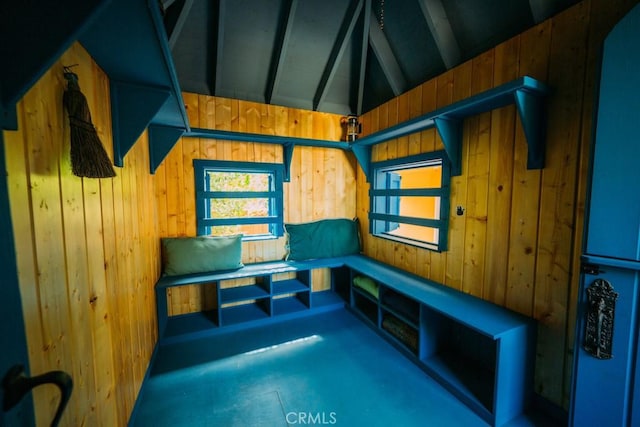 mudroom with a wealth of natural light, vaulted ceiling with beams, and wooden walls