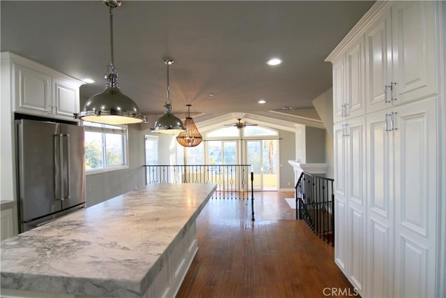 kitchen featuring lofted ceiling, high quality fridge, white cabinetry, hanging light fixtures, and dark wood finished floors