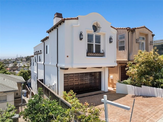 1612 Speyer Ln, Redondo Beach, CA 90278 - mediterranean / spanish house featuring a tiled roof, an attached garage, a chimney, stucco siding, and driveway