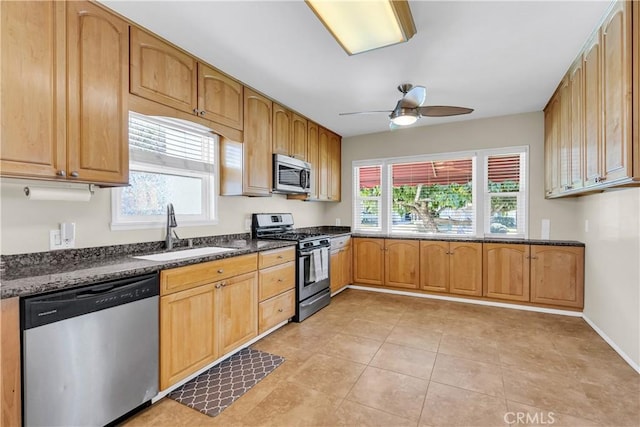 kitchen featuring light tile patterned floors, ceiling fan, stainless steel appliances, dark stone counters, and sink