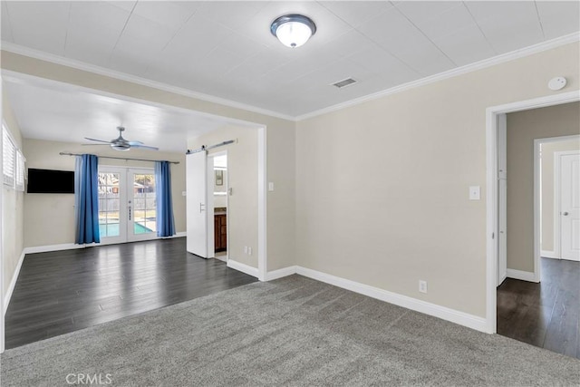 unfurnished living room featuring ornamental molding, dark carpet, a barn door, and french doors