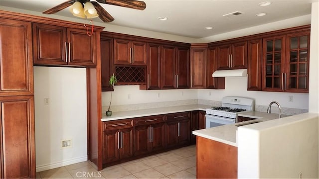 kitchen with light tile patterned floors, white gas range oven, and ceiling fan