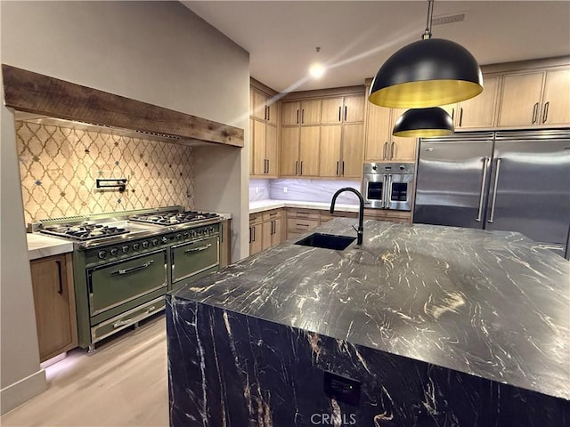 kitchen featuring tasteful backsplash, sink, stainless steel appliances, custom range hood, and dark stone counters