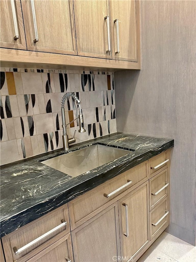 kitchen with sink, light tile patterned floors, and dark stone counters