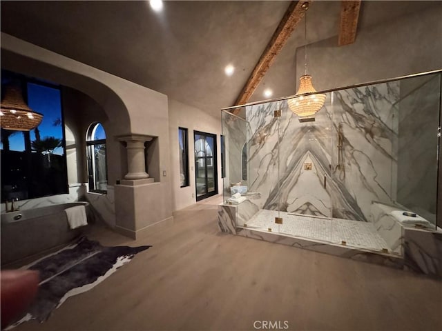 interior space featuring vaulted ceiling with beams, wood finished floors, and ornate columns