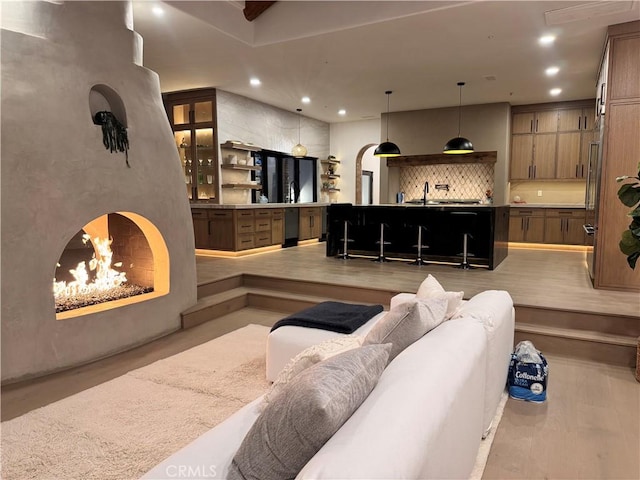 living area featuring a warm lit fireplace, arched walkways, and recessed lighting