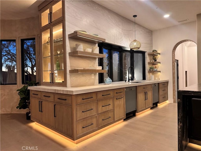 bar with visible vents, arched walkways, dishwasher, hanging light fixtures, and a sink