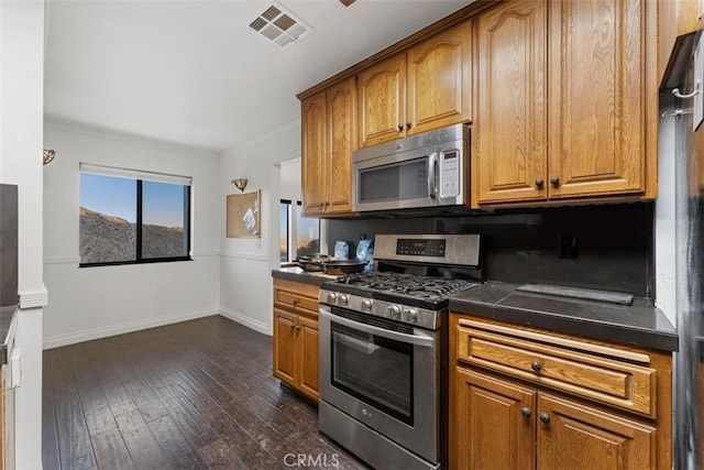 kitchen featuring appliances with stainless steel finishes, decorative backsplash, and dark hardwood / wood-style floors