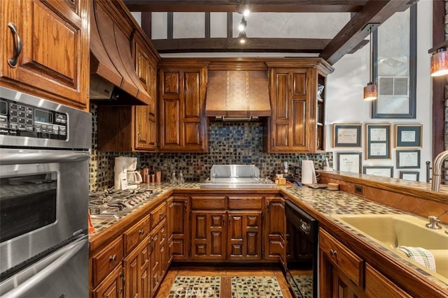 kitchen featuring premium range hood, stainless steel appliances, tasteful backsplash, wall chimney exhaust hood, and sink