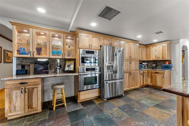 kitchen featuring stainless steel appliances, tasteful backsplash, and light stone countertops