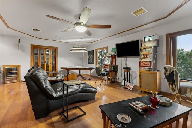 living room featuring light wood-type flooring, ceiling fan, a healthy amount of sunlight, and beverage cooler