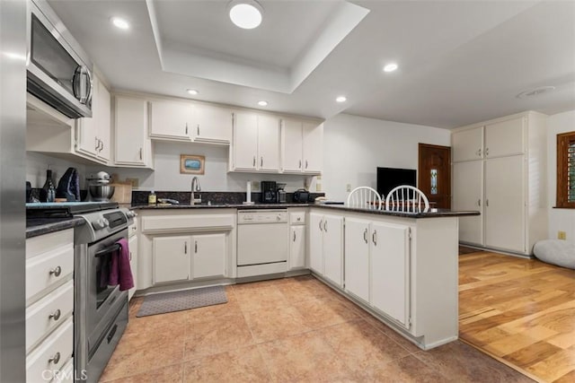 kitchen with sink, white cabinetry, kitchen peninsula, and stainless steel appliances