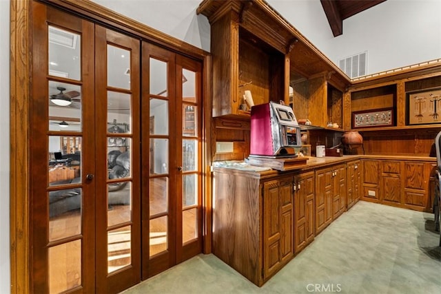 interior space featuring light carpet, vaulted ceiling with beams, french doors, and built in desk