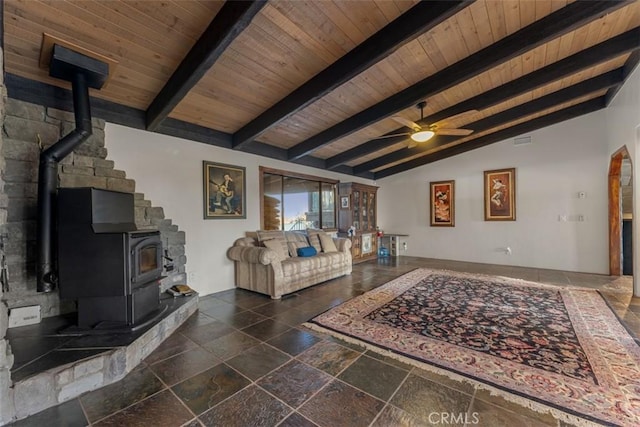 living room featuring ceiling fan, a wood stove, lofted ceiling with beams, and wooden ceiling