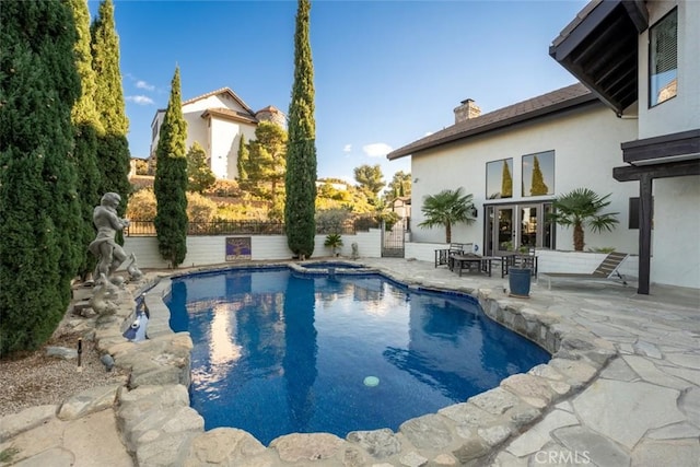 view of pool with french doors, a patio, and an in ground hot tub