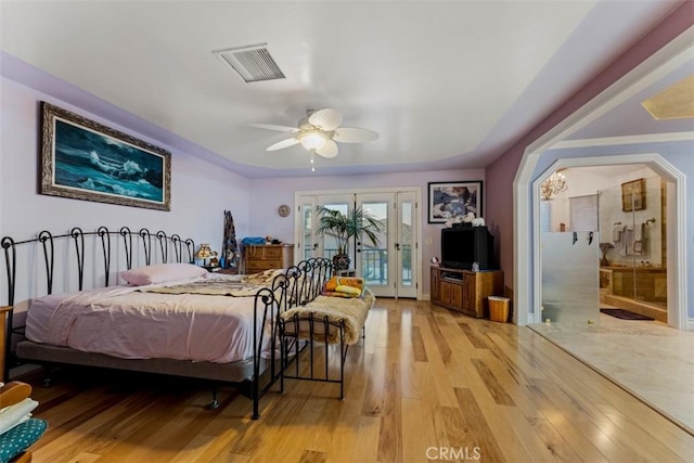 bedroom featuring ensuite bathroom, access to exterior, light hardwood / wood-style floors, and ceiling fan with notable chandelier