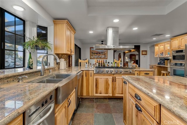 kitchen featuring light stone countertops, island exhaust hood, stainless steel appliances, light brown cabinetry, and sink