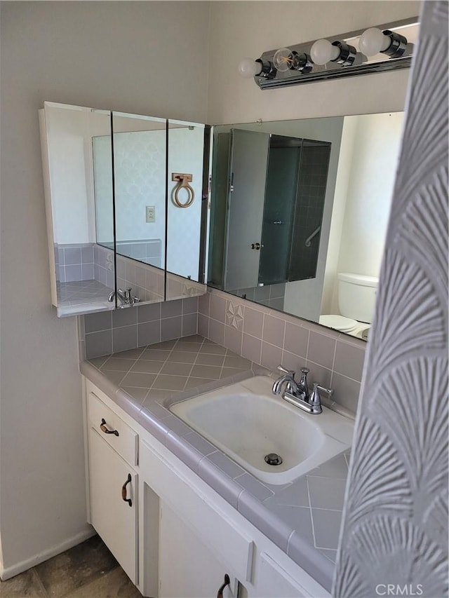 bathroom with toilet, vanity, and backsplash