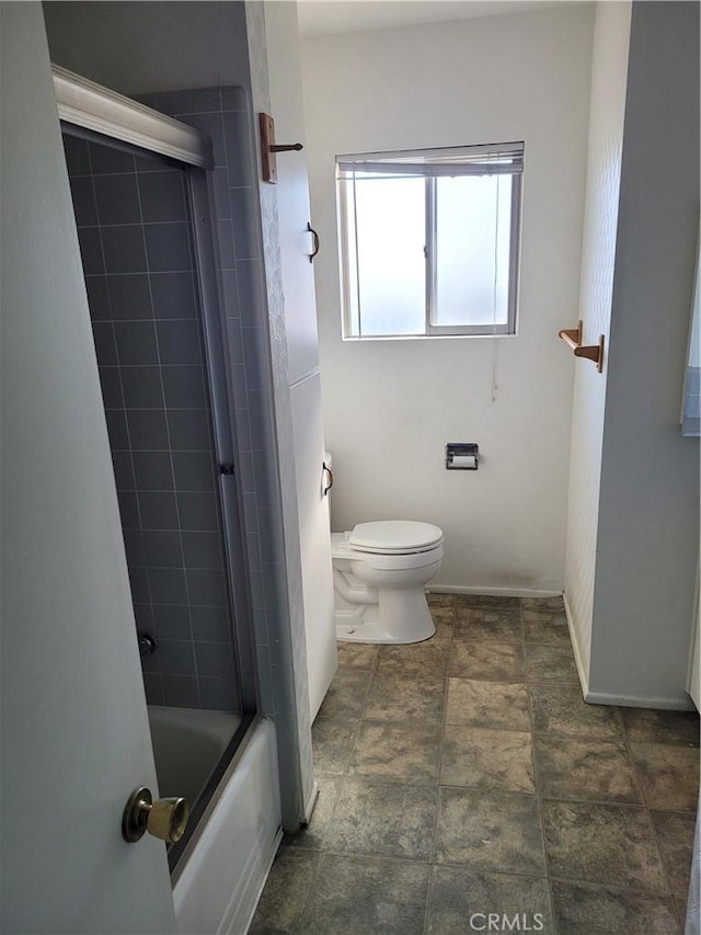 bathroom featuring toilet and bath / shower combo with glass door