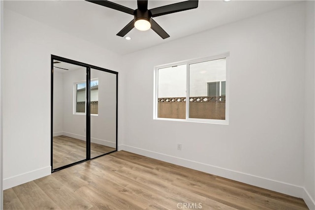 unfurnished bedroom with ceiling fan, a closet, and light wood-type flooring