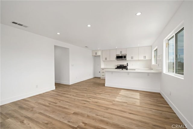 unfurnished living room with sink and light hardwood / wood-style floors