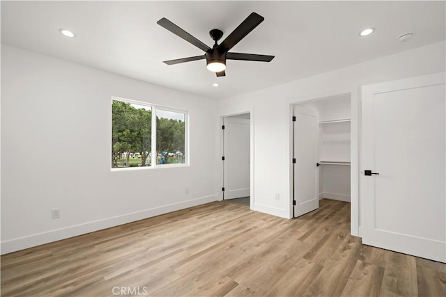 unfurnished bedroom featuring ceiling fan, a closet, a walk in closet, and light wood-type flooring