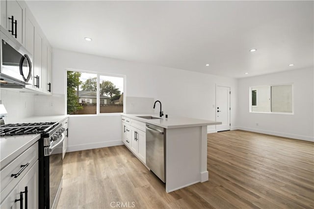 kitchen with white cabinetry, stainless steel appliances, tasteful backsplash, light wood-type flooring, and sink