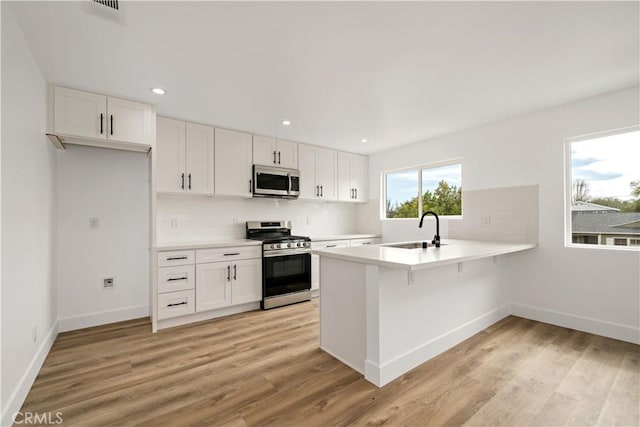 kitchen featuring sink, white cabinetry, kitchen peninsula, and stainless steel appliances