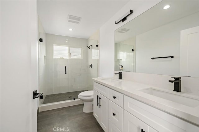 bathroom with toilet, vanity, and a shower with shower door