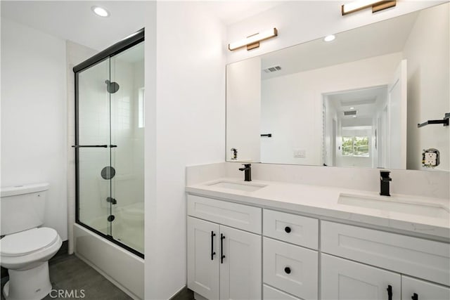 full bathroom with toilet, bath / shower combo with glass door, and vanity