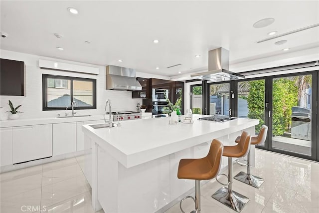 kitchen with wall chimney exhaust hood, a kitchen island, white cabinetry, french doors, and sink