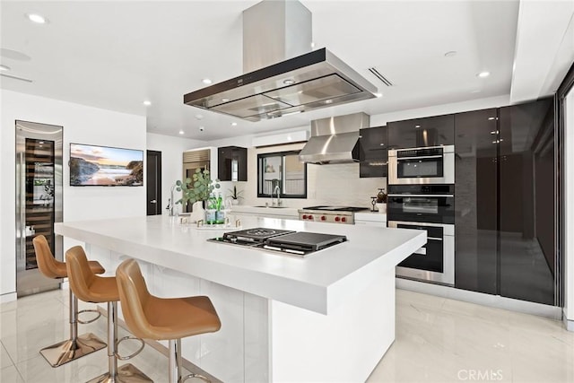 kitchen featuring a center island with sink, island exhaust hood, stainless steel appliances, wall chimney exhaust hood, and beverage cooler