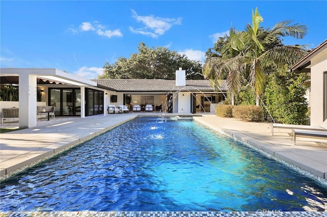 view of swimming pool with pool water feature and a patio