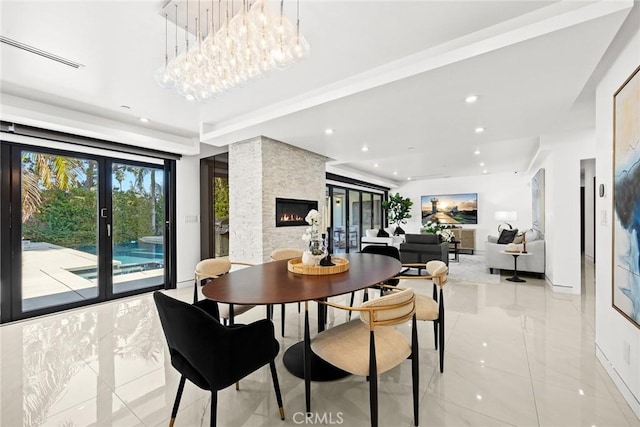 dining space featuring a chandelier, a stone fireplace, and light tile patterned flooring