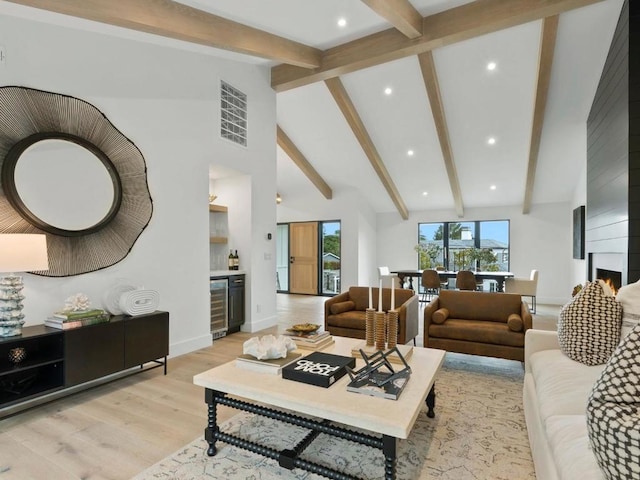 living room featuring beverage cooler, beamed ceiling, a fireplace, light hardwood / wood-style floors, and high vaulted ceiling