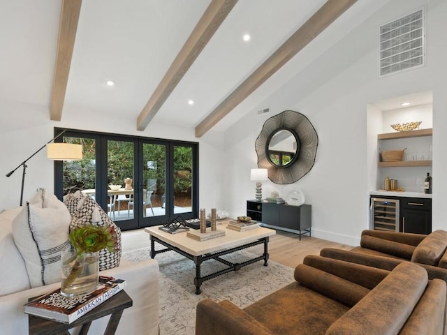 living room featuring bar, beverage cooler, french doors, beam ceiling, and light hardwood / wood-style flooring