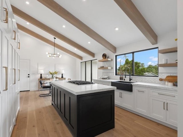 kitchen with hanging light fixtures, sink, white cabinetry, and a center island